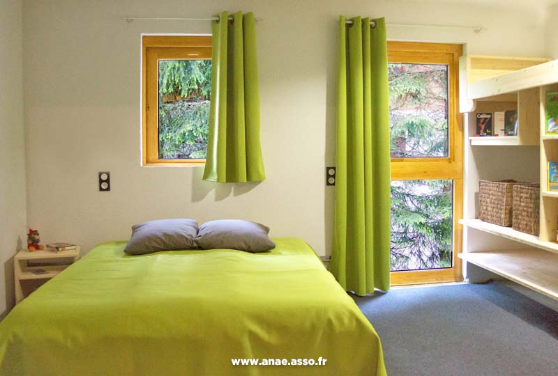 Chambre double rénovée avec un lit couleur vert d'eau - les rideaux sont assortis aux tons de la chambre