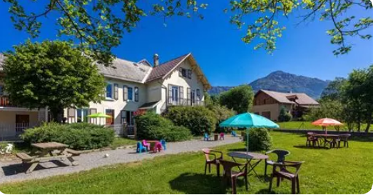 maison entourée de verdure, de montagne et d'un ciel bleu